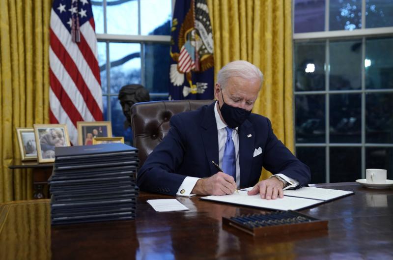 President Biden signs his first executive action in the Oval Office on Wednesday afternoon. Evan Vucci/AP