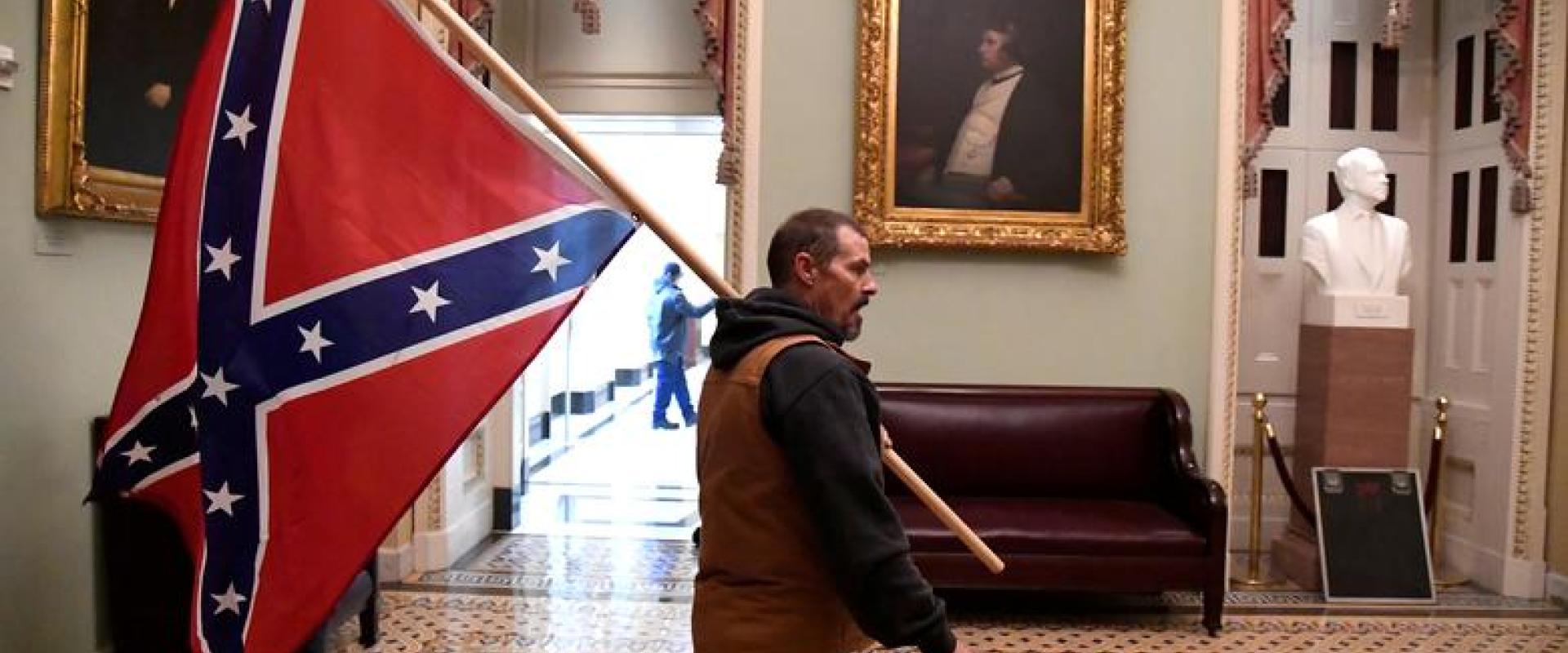 كيفين سيفريد يحمل علم معركة الكونفدرالية في الطابق الثاني من مبنى الكابيتول بالقرب من مدخل مجلس الشيوخ أثناء اقتحام مبنى الكابيتول ، نقلا عن رويترز